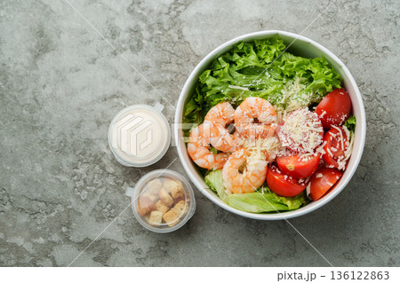 Fresh shrimp salad with lettuce and tomatoes served in a bowl with dressing and croutons 136122863