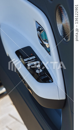 Door panel with window controls and speaker near car entrance 136122901