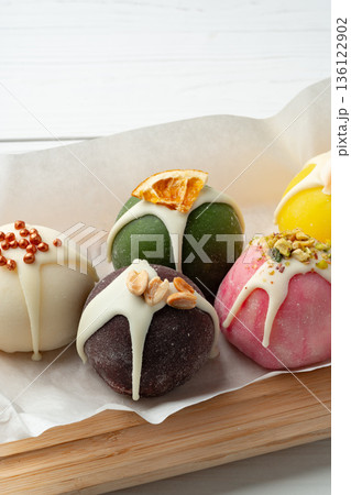 Colorful dessert balls sit on a tray with dripping icing and toppings in a bright setting 136122902