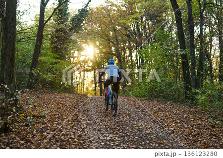 Cyclist on Forest Trail at Sunset: Autumn Ride Through Leaves and Sunlight, Energetic Nature Escape Cyclist on Forest Trail at Sunset: Autumn Ride Through Leaves and Sunlight, Energetic Nature Escape 136123280