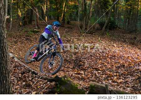 Mountain Biker Navigates Leafy Forest Trail on a Sunny Autumn Day Mountain Biker Navigates Leafy Forest Trail on a Sunny Autumn Day 136123295