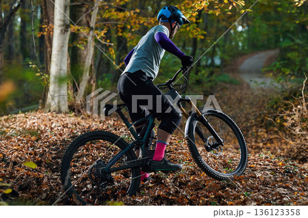 Autumn Mountain Bike Ride Through Leafy Trail With Rider Wearing Helmet And Protective Gear Autumn Mountain Bike Ride Through Leafy Trail With Rider Wearing Helmet And Protective Gear 136123358