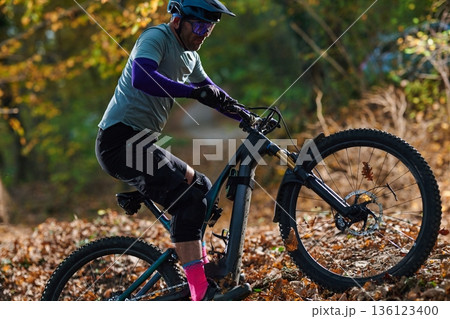 Mountain Biker Riding Through Autumn Forest Trail in Outdoor Adventure Scene With Gear 136123400