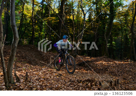 Autumn Forest Mountain Biker Riding Through Leaves On a Rugged Trail Autumn Forest Mountain Biker Riding Through Leaves On a Rugged Trail 136123506