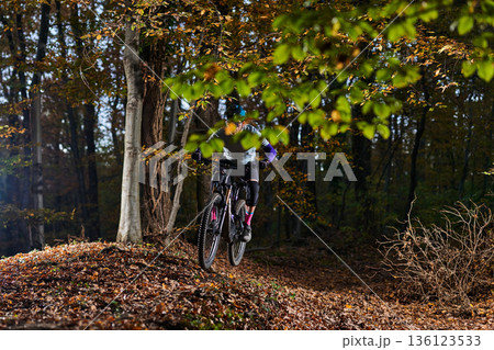 Autumn Forest Mountain Biking Action: Rider Jumping Over Leafy Trail in Colorful Fall Autumn Forest Mountain Biking Action: Rider Jumping Over Leafy Trail in Colorful Fall 136123533