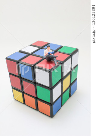 Miniature Reader Sitting Quietly Atop Colorful Rubik Cube 136123891
