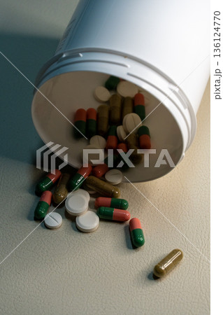 Pills and capsules spilling from medical bottle 136124770