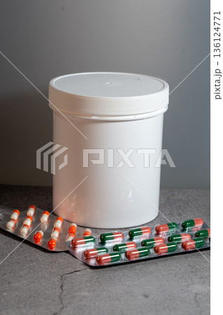 White jar and blister packs with medicine capsules 136124771