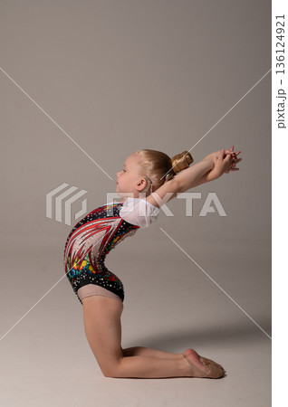 Rhythmic gymnastics child with cochlear implant performing backbend exercise. Hearing loss treatment, cochlear implantation recovery, body awareness, inclusive training, and pediatric rehabilitation Rhythmic gymnastics child with cochlear implant performing backbend exercise. Hearing loss treatment, cochlear implantation recovery, body awareness, inclusive training, and pediatric rehabilitation 136124921