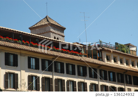 facade with multiple windows and red geraniums on top facade with multiple windows and red geraniums on top 136124932