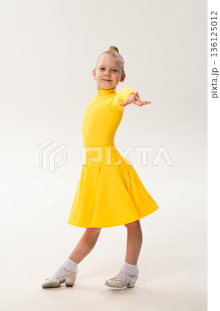 Young girl with cochlear implant performing dance pose in studio. Hearing impairment rehabilitation, auditory therapy, assistive hearing technology, inclusive childhood development, and confidence 136125012