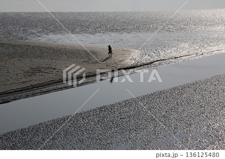 During low tide the water in the river Matla falls so low that people walk to the other shore in Canning Town, India 136125480