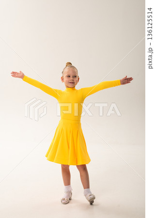 Little girl in yellow dress dancing with cochlear implant. Overcoming hearing loss through rhythm, art, inclusion, and strength of spirit in artistic gymnastics and ballroom dance. Little girl in yellow dress dancing with cochlear implant. Overcoming hearing loss through rhythm, art, inclusion, and strength of spirit in artistic gymnastics and ballroom dance. 136125514