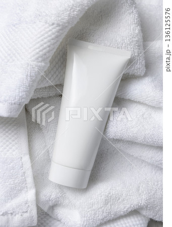 Mockup of white blank squeeze cosmetic tube on white bath terry towel. Spa hotel context 136125576