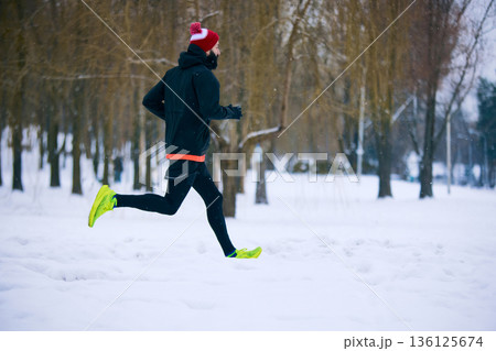 Male runner training in snowy winter park. Male runner training in snowy winter park. 136125674