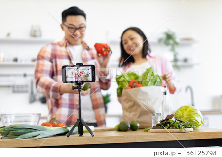 A smiling couple records a cooking video in their bright, modern kitchen A smiling couple records a cooking video in their bright, modern kitchen 136125798