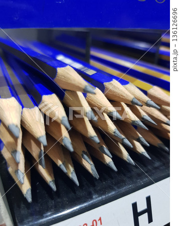 Many blue pencils are lined up with sharpened tips pointing outward. 136126696