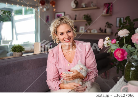 Woman smiling holding cat feeling happy at home Woman smiling holding cat feeling happy at home 136127066