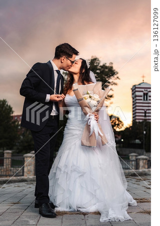Interracial wedding couple kissing during beautiful sunset 136127099