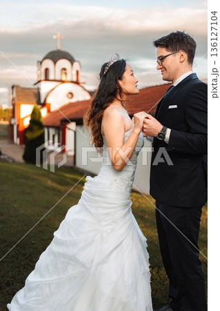 Interracial couple holding hands at wedding outside Orthodox chu Interracial couple holding hands at wedding outside Orthodox chu 136127104