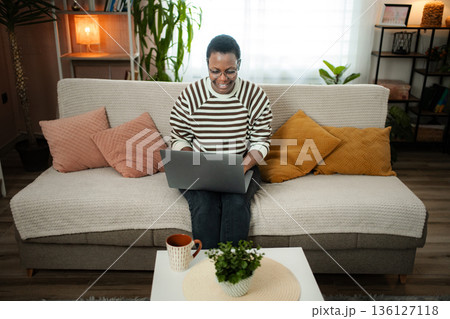 Happy adult woman working from home using laptop Happy adult woman working from home using laptop 136127118