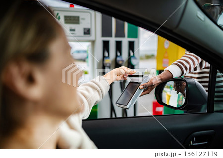 Woman making credit card payment at gas station pump Woman making credit card payment at gas station pump 136127119