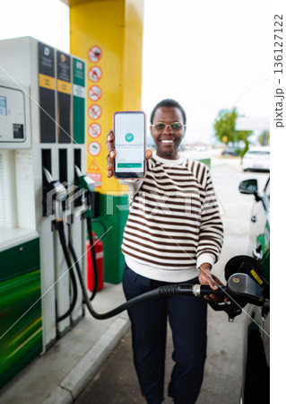 Woman refueling car showing successful mobile payment at gas station Woman refueling car showing successful mobile payment at gas station 136127122