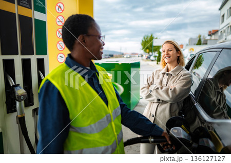 Gas station worker refueling car for smiling customer 136127127