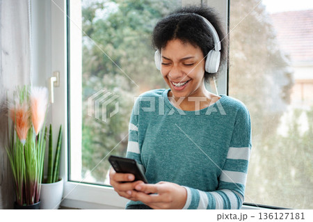 Young black woman laughing listening music using smartphone 136127181