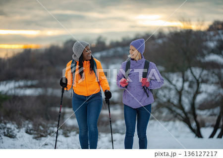 Two women hiking in snow enjoying winter outdoor activity and friendship 136127217