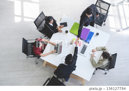Top view of business partners shaking hands over the table after concluding a business agreement in meeting room with the team. Business to succeed concept. Top view of business partners shaking hands over the table after concluding a business agreement in meeting room with the team. Business to succeed concept. 136127784