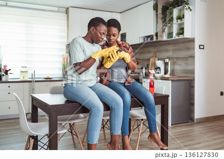 Two young women taking a break from cleaning the kitchen and using a smartphone 136127830