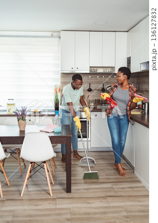 Young couple sweeping and cleaning their kitchen floor 136127832