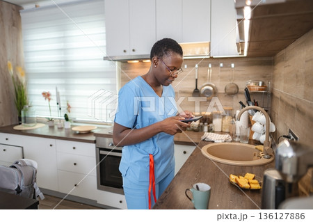 Nurse using smartphone in kitchen during break time Nurse using smartphone in kitchen during break time 136127886