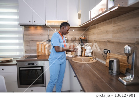 Nurse washing a glass in the kitchen sink Nurse washing a glass in the kitchen sink 136127901