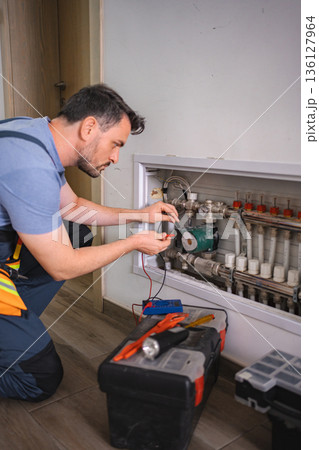 Technician checking domestic heating system with multimeter Technician checking domestic heating system with multimeter 136127964