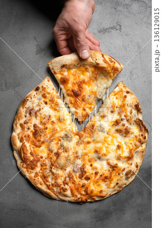 Hand taking slice of cheese pizza with melted cheese Hand taking slice of cheese pizza with melted cheese 136129015