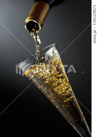 White sparkling wine is poured from a bottle into a glass. 136129071