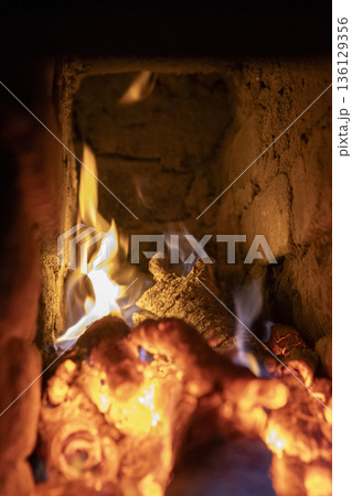 A fireplace with blazing wood. An antique brick hearth for warming the room. 136129356