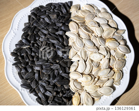 Healthy snack of mixed black sunflower and white pumpkin seeds. Healthy snack of mixed black sunflower and white pumpkin seeds. 136129361