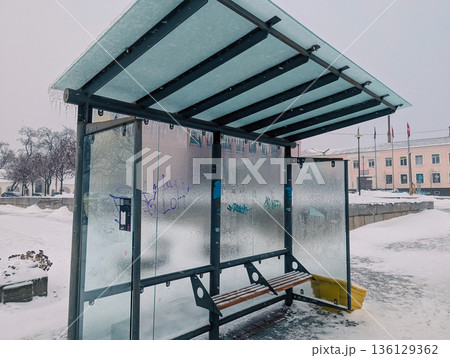 An ice-covered glass bus stop with an empty bench in the city An ice-covered glass bus stop with an empty bench in the city 136129362