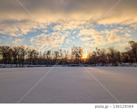 Sunset with orange clouds over a frozen winter lake Sunset with orange clouds over a frozen winter lake 136129384