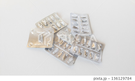 Empty foil blister packs for various tablets and capsules isolated on white background. Used medications. Healthcare and drug concept. Empty foil blister packs for various tablets and capsules isolated on white background. Used medications. Healthcare and drug concept. 136129784
