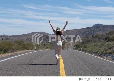 Tourist walking in the middle of a desert road enjoying freedom and adventure Tourist walking in the middle of a desert road enjoying freedom and adventure 136129844