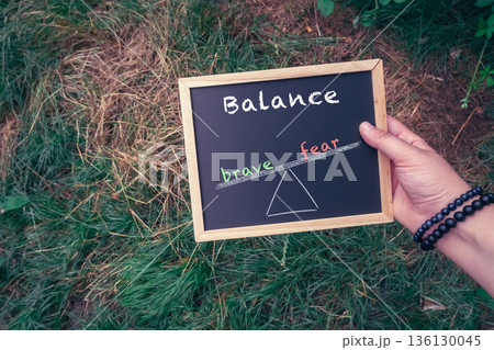 Person holds a chalkboard with the words balance and fear written on it Person holds a chalkboard with the words balance and fear written on it 136130045