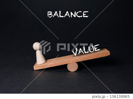 Wooden balance scale with a pawn figure representing value and equilibrium concept 136130065