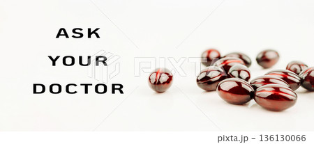 Red capsules scattered on a white surface with a health message for medical advice Red capsules scattered on a white surface with a health message for medical advice 136130066