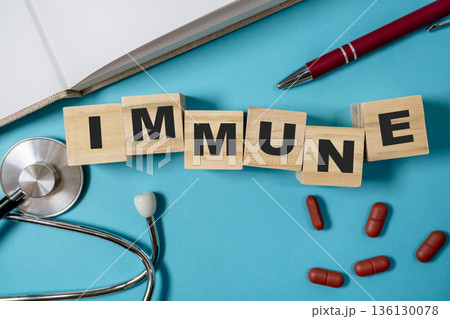 Immune health concept with wooden blocks, stethoscope, and red capsules on blue background 136130078