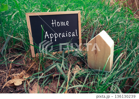Home appraisal sign with wooden house model in lush green grass showcasing real estate concept 136130239