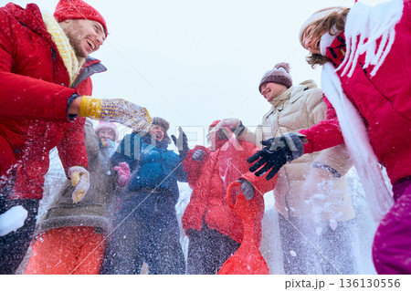 Group of friends throwing snow and laughing outdoors. 136130556